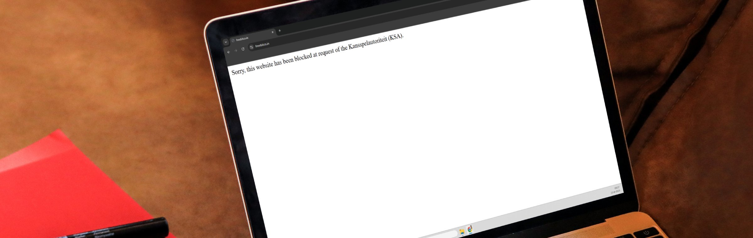Mock-up van een laptop met een melding op de website freebitco.in van een blokkade van de Kansspelautoriteit.